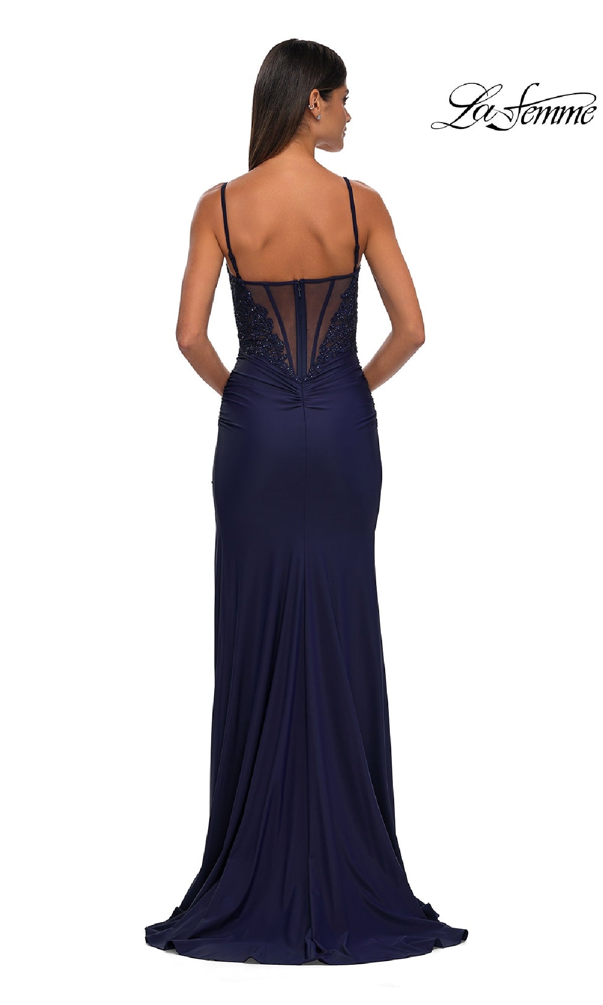 A woman seen from behind wears the Lace-Corset Long Jersey Prom Dress (La Femme 32803)—navy blue, floor-length, with thin straps, beaded lace-corset bodice, and sheer back.